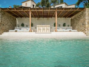 een patio met een tafel en stoelen naast het water bij Villa Azure 8p. - Zazu Villas in Girona