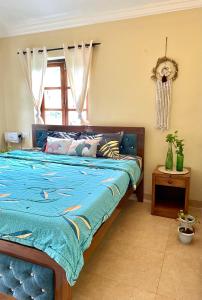 a bedroom with a bed with a blue comforter and a window at NATURES HAVEN By Goaround Homes at Vagator in Vagator