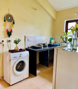 uma cozinha com uma máquina de lavar roupa e um lavatório em NATURES HAVEN By Goaround Homes at Vagator em Vagator