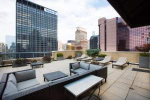 a rooftop patio with couches and tables and a city skyline at Midtown 2BR w Pool Gym Roof nr Broadway NYC-382 in New York