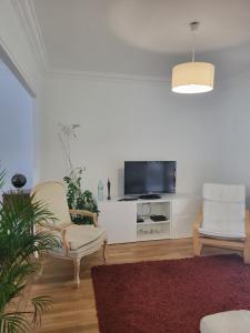 een woonkamer met 2 stoelen en een flatscreen-tv bij Maison à louer 3 chambres in Sartrouville