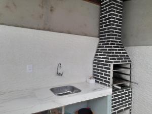 a kitchen with a sink and a brick oven at Casa de praia com piscina in Itanhaém