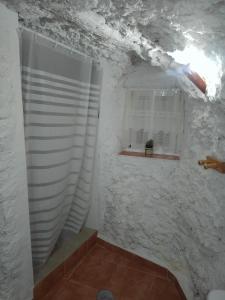 y baño con paredes de mármol blanco y ducha. en Casa/Cueva el Cigarrillo, en Pegalajar