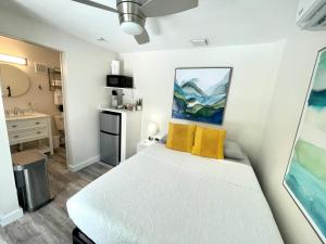 1 dormitorio con cama blanca y almohadas amarillas en The Agustin Guesthouse - Men Only Clothing Optional en Fort Lauderdale