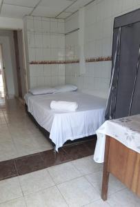 um pequeno quarto com uma cama com lençóis brancos em Alojamiento cómodo en una ubicación maravillosa! em Cartagena das Índias