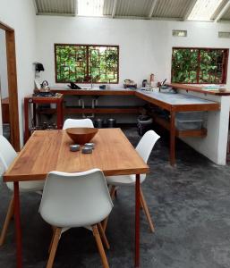 a dining room with a wooden table and white chairs at Casa Bolita in Dos Brazos