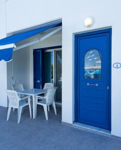 een blauwe deur op een gebouw met een tafel en stoelen bij Stegna-TULA in Archangelos