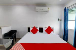 a bedroom with a red and white bed and a chair at Super OYO Flagship Blue Beach Cottage in Gopālpur
