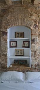 a bedroom with a stone wall with a bed and framed pictures at THE GARDEN OF CHIOS in Chios