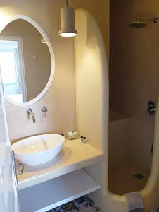 La salle de bains est pourvue d'un lavabo blanc et d'un miroir. dans l'établissement Anemousa Hotel, à Folégandros