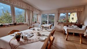 une salle à manger avec deux tables et de grandes fenêtres dans l'établissement Haus Hepi B&B, à Obertraun