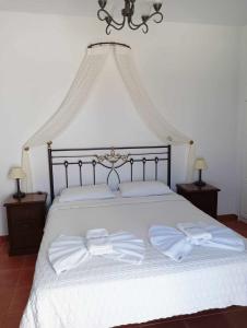 un grande letto bianco con due asciugamani bianchi sopra di Anemousa Hotel a Chora Folegandros