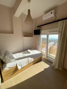 a bedroom with a bed and a large window at Melivoia Apartment in Ayiá