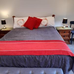 a bed with red and white pillows on it at Papamoa Beach Hugoway, Pohutukawa Studio Deluxe, Close beach, free parking in Papamoa