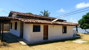 una pequeña casa blanca sentada en la cima de un campo en Casa em Soure Ilha de Marajó., en Soure