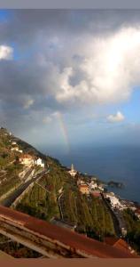 un arco iris en el cielo sobre una ciudad y el océano en LA CASA DEL CAPITANO furore amalfi coast, en Furore