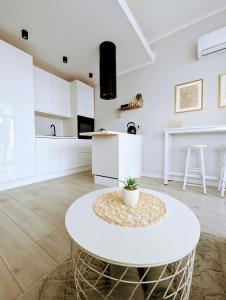 a white kitchen with a round table in a room at White Suite, 50 meters to beach, 10th floor, beautiful view, Baltic Best in Dziwnówek