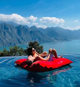 zwei Personen, die auf einem anlagbaren Floß im Wasser reiten in der Unterkunft Esprit D'Hotel Panoramico in Fonteno