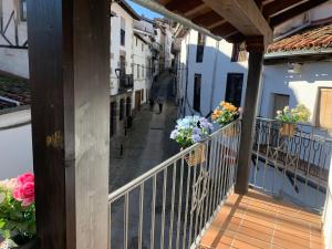 un balcón con flores en cestas en un edificio en La Estrella de David, Apartamentos Rurales, en Hervás