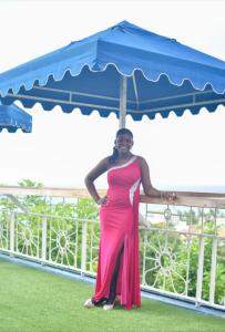 a woman in a pink dress standing under an umbrella at Big Apple Hotel in Montego Bay