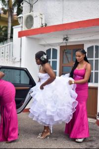 zwei Frauen in Kleidern stehen neben einem Auto in der Unterkunft Big Apple Hotel in Montego Bay