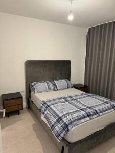 1 dormitorio con 1 cama con manta azul y blanca en Spacious 2 Bedroom Flat With Balcony en Barking