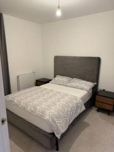 a bed in a bedroom with two night stands and two tables at Spacious 2 Bedroom Flat With Balcony in Barking