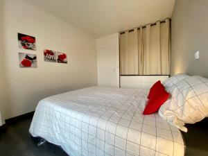 a bedroom with a bed with a red pillow at Appartement terrasse proche Versailles in Élancourt