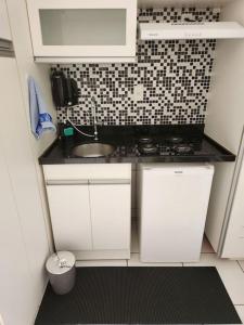 eine kleine Küche mit weißen Schränken und einem Waschbecken in der Unterkunft Aconchegante apart no Park Sul in Brasilia