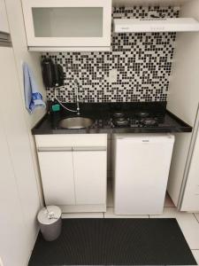 Una pequeña cocina con gabinetes blancos y un fregadero. en Aconchegante ap no Park Sul próximo ao aeroporto, en Brasilia