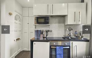 a kitchen with white cabinets and a stove top oven at Luxury city centre Apartment in London