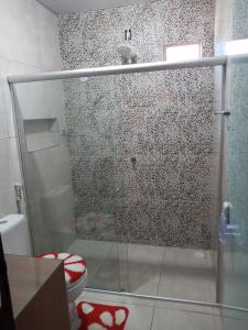 La salle de bains est pourvue d'une douche en verre et de toilettes. dans l'établissement Casa Martins, à São Miguel dos Milagres