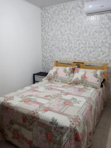 um quarto com uma cama com uma colcha floral em Casa Martins em São Miguel dos Milagres