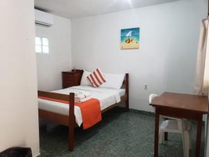 a small bedroom with a bed and a desk at Beach Club Budget Rooms at Popeyes Caye Caulker in Caye Caulker