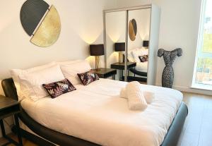 um quarto com uma cama com almofadas e um espelho em Urban Gateway Spacious Apartment with free parking em Bracknell