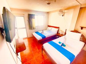 a hotel room with two beds and a flat screen tv at HISTORICO HOSTAL ELIZABETH in Puerto Ayora