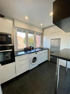 a kitchen with a washer and dryer in it at Appartement terrasse proche Versailles in Élancourt
