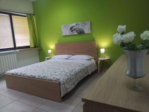 un dormitorio verde con una cama y un jarrón de flores en TWIN HOUSE en Tito