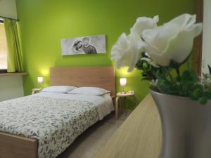 1 dormitorio con 1 cama y un jarrón con flores blancas en TWIN HOUSE en Tito