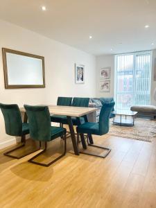 ein Esszimmer mit einem Holztisch und grünen Stühlen in der Unterkunft Urban Gateway Spacious Apartment with free parking in Bracknell