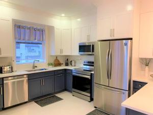 a kitchen with white cabinets and a stainless steel refrigerator at Jamaica Bookings in Montego Bay