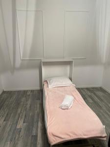 un piccolo letto con una coperta rosa in una stanza di Dielli Apartment New a Pristina