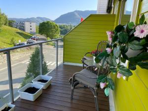 a porch with two chairs and flowers on a balcony at 84m2 3 sleeping rooms which direct traffic to airport and city center in Bergen