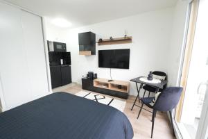a bedroom with a bed and a table and a tv at Noisy-le-Grand : Superbe appartement lumineux in Noisy-le-Grand