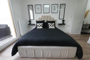 a bedroom with a large bed with black sheets and pillows at Noisy-le-Grand : Superbe appartement lumineux in Noisy-le-Grand