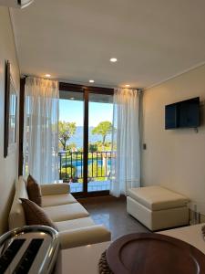 - un salon avec un canapé et une grande fenêtre dans l'établissement Apart Hotel Sol y Lago, à Pucón