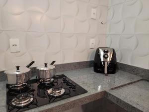 a stove with two pots and a toaster on a counter at Flats Ipê in Pirenópolis