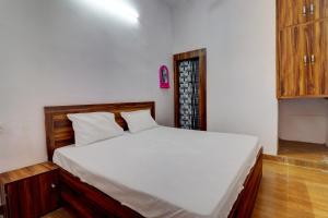 a bedroom with a large bed with white sheets at OYO Hotel Pitra Chaaya Hotel And Restaurant in Mathura