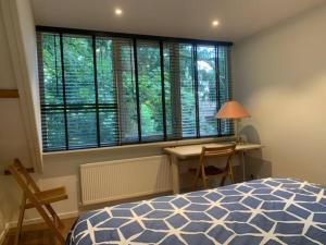 a bedroom with a bed and a desk and a window at Private House ‘Het Dwerghuys’ - also longstays in Doorn