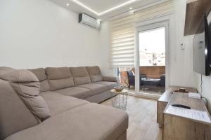 a living room with a couch and a large window at KAAN APARTMENT in Budva
